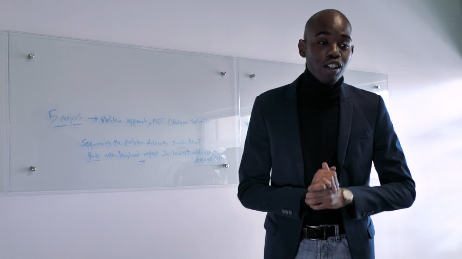 A trainer in a dark jacket presenting at a whiteboard